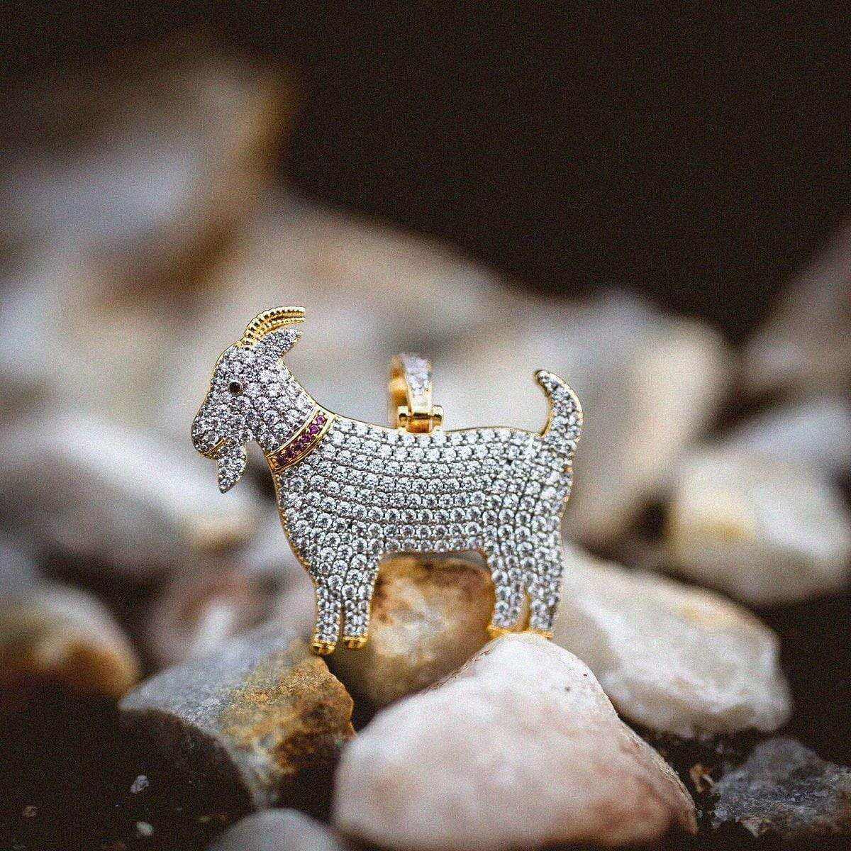 GOAT Pendant with a red collar, covered in corresponding colored CZ stones, pictured on a rocky landscape. 