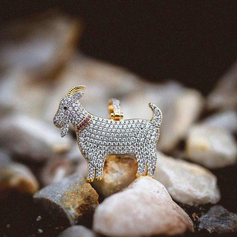 GOAT Pendant with a red collar, covered in corresponding colored CZ stones, pictured on a rocky landscape. 